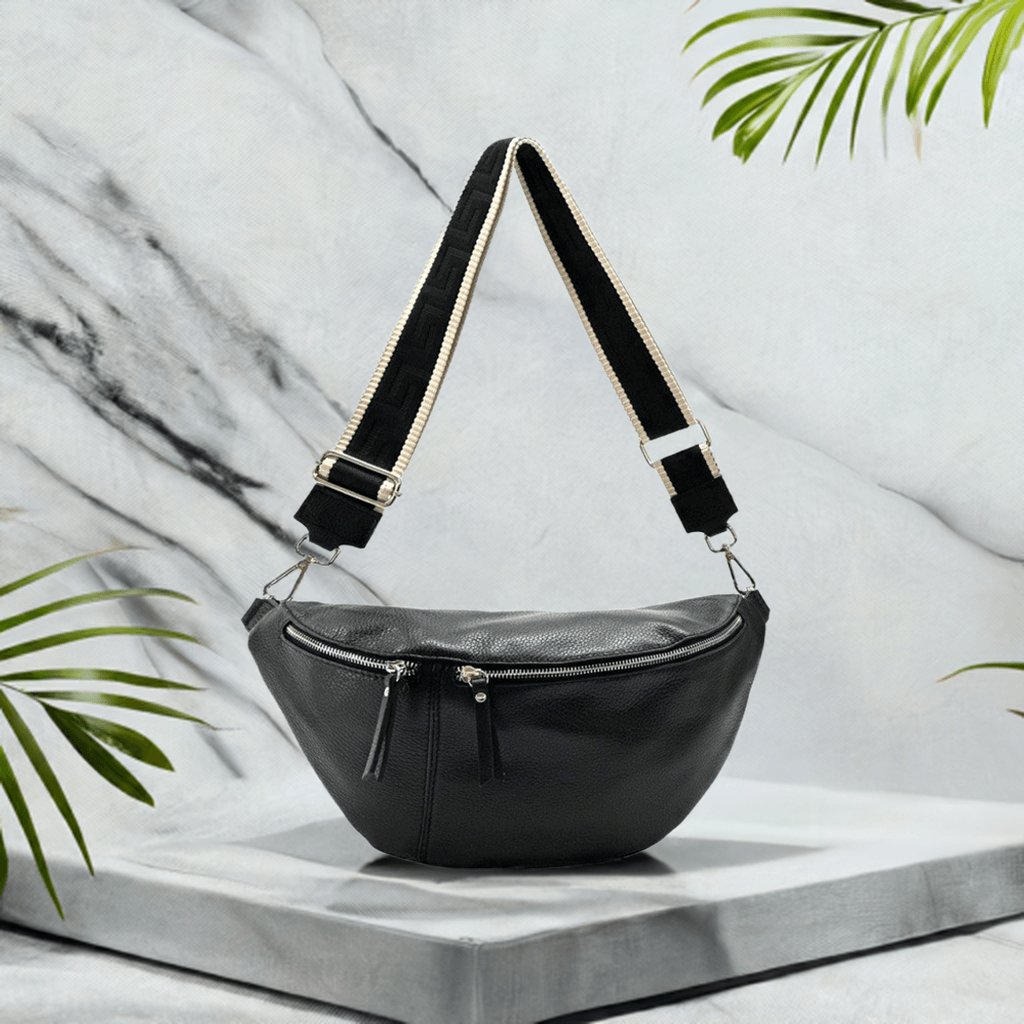 Nova Crossbody Fanny Pack 2 in black Italian leather with dual detachable straps against a marble background.