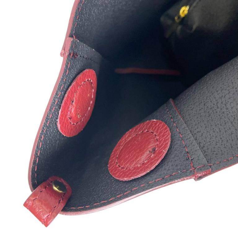 Interior view of an elegant Italian leather handbag with red magnetic buttons for size adjustment.