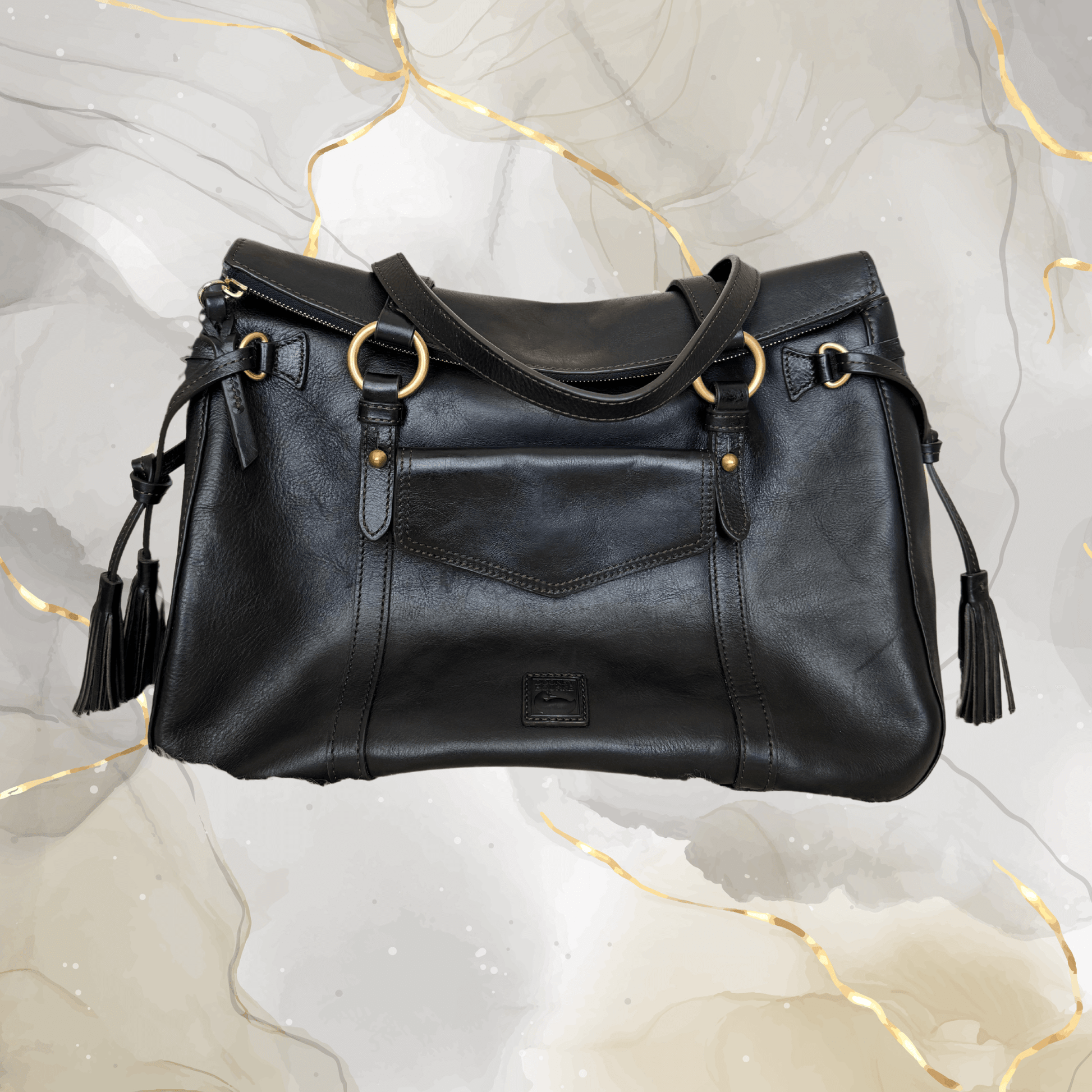 Pre-owned Dooney & Bourke Florentine Leather Satchel in black with tassel accents on a marble background.